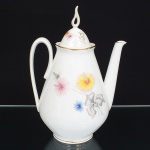 Porcelana Real, Mauá - SP(Fundada em 1943 por Fritz Erwin Schmidt). Bule para café em porcelana nacional da década de 1960, esmaltagem vítrea na cor branca, corpo cônico assentado sobre base circular, decoração aplicada por estampagem policromada, com motivos florais estilizados compostos por flores radiais em tons de rosa e amarelo, acompanhadas por folhas em grisaille, distribuídos no corpo e na tampa, tampa abaulada com pega vazada elevada, moldada na própria porcelana, filetes dourados aplicados na borda superior do corpo e na aba da tampa, alça lateral curvada, bico vertedor rtilíneo de seção tubular. Marca da manufatura no verso. Medidas: Alt.: x Comp.: x Larg.: