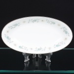 NORITAKE, Nagoya - Japão(Fundada em 1904 pelos irmãos Ichizaemon e Toyo Morimura). Elegante travessa oblonga, de interior ligeiramente côncavo, em porcelana japonesa da década de 1960/70. Padrão 'WELLESLEY 6214', produzido entre os anos de 1961 a 1976. Esmaltagem vítrea na cor branca, decorada com delicado padrão floral com flores brancas, folhas em suave tons de verde e outros tons pastéis, borda contornada por friso em platina. Marca da manufatura no verso. Med.: Alt. 3,5 x Comp. 23 x Larg. 12,5 cm.