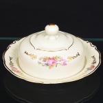 KPM - Krister Porzellan-Manufaktur, Waldenburg - Alemanha(Fundada em 1831 por Karl Kristen). Excepcional cremeira em porcelana, de manufatura alemã, fabricada na polônia entre anos de 1930 -1945, modelo Friederike, citado na Enciclopédia de Porcelana da Silésia Volume I. Executado ao estilo renascentista. Esmaltagem vítrea na cor branca, modelada com elementos fitomorfos em relevo, decorada com buquês e flores soltas em estampagem policromada, realçada com generosos arremates de frisos, e faixas, em pintura à ouro; tampa campaniforme encimada por puxador em feitio de fruto, presentoir com redoma central e borda recortada. Marca da manufatura no verso. Med.: Alt. 10 x Diam. 19 cm.