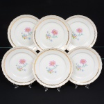 Porcellana Mauá, Mauá - SP(Fundada em 1937 por Fritz Erwin Schmidt / ativa até 1968). Conjunto de pratos fundos em porcelana nacional da década de 1950/60; esmaltagem vítrea na cor branca, centro decorado com crisântemo e folhagens em estampagem policromada, predominando as tonalidades violeta, rosa, azul e verde; borda recortada em ondualções decorada com aplicações de filete dourado, orla circundada por volutas relevadas na própria pasta, e faixa contínua de folhagens aplicada em douradura. Marca da manufatura no verso. Composto de seis(06) unidades. Medidas: Diam.: 23 cm.