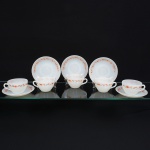 Conjunto de xícaras para chá em vidro opalinado de tonalidade branco leitoso, dotada de decoração com flores e galhos aplicada por estampagem de tonalidade castanho e laranja, padrão decorativo replicado no pires; bojo hemisférico com alça lateral curvada. Fabricado no Brasil pela empresa Brasividro S.A., sob a marca Termo-Rey, durante a década de 1970. Meds.: Xícara: Alt. 6 x Comp.: 11,5 x Larg.: 10 cm. Pires: Diam.: 15,5 cm.