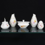 Cinco(05) itens: a) Porcelana Real, Mauá - SP(Fundada em 1943 por Fritz Erwin Schmidt). Duas galhetas, um saleiro e um pimenteiro em porcelana nacional, esmaltação branca, decoração aplicada por estampagem policromada, com motivos florais estilizados compostos por flores radiais em tons de rosa e amarelo, acompanhadas por folhas em grisaille, distribuídos no corpo, realçado por frisos em douradura. Marca da manufatura ao fundo. Medidas: Galhetas: Alt.: 11,5 x Diam.: 6,5 cm; Saleiro: Alt.: 7 x Diam.: 5 cm; Pimenteiro: Alt.: 9 x Diam.: 7 cm. b) Porcelana Real, Mauá - SP(Fundada em 1943 por Fritz Erwin Schmidt). Mostardeira com tampa em porcelana nacional, esmaltagem vítrea na cor branca, formato oblongo, borda contornada por friso prateado, decoração floral em policromia, tampa reta encimada por puxador obcônico. Marca da manufatura ao fundo. Medidas: Alt.: 6,5 x Comp.: 11 x Larg.: 7,5 cm.