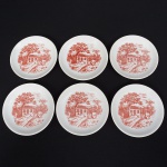 Conjunto de seis(06) porta-copos em porcelana branca, de aba lisa e cavado central raso, decoração aplicada por transferência monocromática em vermelho, representando cena rural composta por casa, perosonagens em atividade cotidiana, árvore de grande porte em primeiro plano, vegetação tropical e caminho sinuoso. Medida: Diam.: