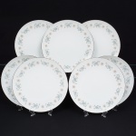 NORITAKE, Nagoya - Japão(Fundada em 1904 pelos irmãos Ichizaemon e Toyo Morimura). Elegante conjunto de pratos rasos para jantar em porcelana japonesa da década de 1960/70. Padrão 'WELLESLEY 6214', produzido entre os anos de 1961 a 1976. Esmaltagem vítrea na cor branca, decorada com delicado padrão floral com flores brancas, folhas em suave tons de verde e outros tons pastéis, borda contornada por friso em platina. Marca da manufatura no verso. Composto de sete(07) unidades. Med.: Diam. 27 cm.