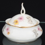 Porcelana Real, Mauá - SP(Fundada em 1943 por Fritz Erwin Schmidt). Açucareiro em porcelana nacional da década de 1960, esmaltagem vítrea na co branca, corpo bojudo, decoração aplicada por estampagem policromada, com motivos florais estilizados compostos por flores radiais em tons de rosa e amarelo, acompanhadas por folhas em grisaille, distribuídos no corpo e na tampa, tampa abaulada com pega vazada elevada, moldada na própria porcelana, filetes dourados aplicados na borda superior do corpo e na aba da tampa. Marca da manufatura no verso. Medidas: Alt.: x Diam.: