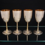 EBERLE. Belíssimo conjunto de cálices  de pé alto confeccionado em metal espessurado á prata, bojo oval, fuste cilíndrico relevado com sulcos verticais, base ligeiramente abaulada, decorada com futos, folhagens e volutas, borda contornada por perolados, ornatos obtidos através das técnicas do repuxados e cinzelado. Marca da manufatura puncionada no verso. Composto de quatro(04) unidades. Med.: Alt. 18 x Diam. 7 cm.