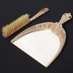 Uma(01) pá e uma(01) escova cata-migalhas confeccionada em metal espessurado à prata, ornamentação vazada e cinzelada com motivo vegetalista, flores, tulipas, e folhagens, cerdas em material sintético. Meds.: Alt. 21 x Comp. 14,5 cm; Comp. 20 cm.