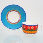Fábrica de Porcelana da Vista Alegre, ílhavo - Portugal(Fundada em 1824 por José Ferreira Basto). Xícara para café da manhã em faiança portuguesa da década de 1980/90, padrão 'Flower Fantasy'; esmaltação branca, dotada de decoração policromada aplicada em estampagem, composta por faixa horizontal com flores estilizadas e elementos geométricos, delimitada por filetes lineares, pires com aba decorada com campo azul uniforme e motivo circular de folhagens estilizadas em nas tonalidades amarelo, azul e vermelho. Marca da manufatura no verso. Medidas: Xícara: 9,5 x Comp.: 15 x Larg.: 11,5 cm; Pires: Diam.: 20,5 cm.