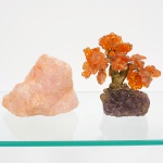 Dois(02) itens; a) Quartzo rosa bruto, fragmento mineral de formato irregular, massa compacta, coloração rosada, superfície natural não lapidada; b) Escultura decorativa representando árvore, com folhas formadas por fragmentos lapidados de cornalina, fixados por fios metálicos; tronco modelado; base constituída por ametista bruta em bloco irregular. Execução por montagem artesanal.