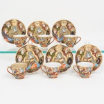 Conjunto de xícaras para café em fina porcelana japonesa, estilo Satsuma de paredes finas, bojo obcônico com alça lateral em arco, interior esmaltado branco e bordas com filete dourado, decoração externa executada em pintura manual policromada com abundante douramento, organizada em campos figurativos contínuos. Os motivos representam figuras humanas masculinas e femininas em trajes cerimoniais, dispostas em composição hierárquica, com personagem central ladeada por figuras secundárias, todas com auréolas douradas e traços faciais delineados, repertório ornamental inclui fundos em esmalte marrom, vermelho, azul e verde, preenchimentos pontilhados, grafismos curvilíneos e reservas delimitadas por linhas douradas em relevo, características do estilo Satsuma. Douramento aplicado em camadas espessas, com relevo perceptível ao tato, empregado tanto no contorno das figuras quanto nos elementos geométricos e simbólicos. Fundo com marca impressa Hand Painted  Made in Occupied Japan, acompanhada de emblema circular com a letra M entre ramos, atribuível a produção japonesa do período do pós-guerra sob ocupação aliada.Produção atribuível ao Japão, período Occupied Japan (circa 19451952). Composto de seis(06) unidades. Medidas: Xícara: 5,5 x Comp.: 8 x Larg. 7 cm. Uma apresenta um bicado na borda.