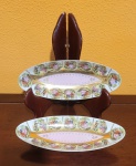Par de covilhetes europeus, antigos,  em porcelana com borda decorada com cenas galantes policromadas. Med.: 25x10cm