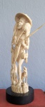 Escultura em marfim (China, século XIX) representando Caçador com animais. Med.: 35cm. Apresenta detalhes com vestígio de colagem no chapéu e em um dos pés.