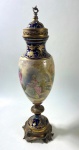 "ANFORA EM PORCELANA DE SEVRES SECULO XIX COM  PINTIURA  FEITA A MAO DE CENA GALANTE SOBRE UMA BASE EM BROZE FUNDO AZUL COBALTO E EOURO TRABALHADO EM FORNO DE MUFLA  DANDO UM ALTO REVEVO NA DOURAÇÃO 50 CM , NO ESTADO NECESSITA RESTAURO ."