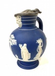 "WEDGWOOD - Jarra em porcelana inglesa da marca Wedgwood, no estilo Neoclássico, nas cores azul claro e aplicações de figuras gregas em branco, tampa em metal. Altura 17 cm"