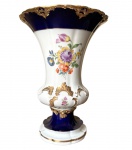 Vaso em porcelana de Meissen, com decoração floral ao centro, em fundo branco, detalhes em dourado em alto relevo e azul cobalto, peça reproduzida no catálogo de Meissen, Alemanha século XIX
