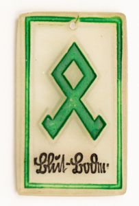 Militaria, Alemanha II Guerra. Proveniente de importante coleção adquirida em Ciney - Bélgica (Feira gigantesca de Militaria). O partido nazista promoveu uma grande arrecadação de fundos antes e durante a guerra com a venda de grande variedade de itens colecionáveis, pins, pendentes, tinnies, badges etc. Todos colecionáveis para incentivar novas compras. Como referência para estudo e identificação aconselhamos o catálogo Donation Badges, Pins & Pendants of the Third Reich de Joseph Cassidy & Christopher Alexander. Oportunidade para colecionador avançado. *Item não promove ou glorifica violência ou intolerância racial. Está à venda apenas para fins de preservação da memória histórica. A Organização do leilão não faz apologia a quaisquer movimentos políticos ou ideológicos, e repudia qualquer ideologia de cunho racista. Runa em vidro. Pág. 17. DJH-40-1. Solo de Sangue - Blut-Boolen. 33x20 mm.