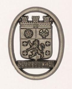 Militaria, Alemanha II Guerra. Proveniente de importante coleção adquirida em Ciney - Bélgica (Feira gigantesca de Militaria). O partido nazista promoveu uma grande arrecadação de fundos antes e durante a guerra com a venda de grande variedade de itens colecionáveis, pins, pendentes, tinnies, badges etc. Todos colecionáveis para incentivar novas compras. Como referência para estudo e identificação aconselhamos o catálogo Donation Badges, Pins & Pendants of the Third Reich de Joseph Cassidy & Christopher Alexander. Oportunidade para colecionador avançado. *Item não promove ou glorifica violência ou intolerância racial. Está à venda apenas para fins de preservação da memória histórica. A Organização do leilão não faz apologia a quaisquer movimentos políticos ou ideológicos, e repudia qualquer ideologia de cunho racista. 1941 - Brasão de armas da fronteira alemã ou cidade ocupada. 38x29 mm. Pág. 237/38. Saarbrucken.
