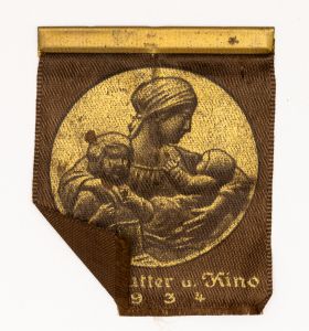 Militaria, Alemanha II Guerra. Proveniente de importante coleção adquirida em Ciney - Bélgica (Feira gigantesca de Militaria). O partido nazista promoveu uma grande arrecadação de fundos antes e durante a guerra com a venda de grande variedade de itens colecionáveis, pins, pendentes, tinnies, badges etc. Todos colecionáveis para incentivar novas compras. Como referência para estudo e identificação aconselhamos o catálogo Donation Badges, Pins & Pendants of the Third Reich de Joseph Cassidy & Christopher Alexander. Oportunidade para colecionador avançado. *Item não promove ou glorifica violência ou intolerância racial. Está à venda apenas para fins de preservação da memória histórica. A Organização do leilão não faz apologia a quaisquer movimentos políticos ou ideológicos, e repudia qualquer ideologia de cunho racista.  1934 - MUK 34-3 - Mãe e criança. Pág. 280. 55x45 mm. Barra em metal com tecido.