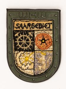 Militaria, Alemanha II Guerra. Proveniente de importante coleção adquirida na Bélgica - Feira de Militaria de Ciney. O partido nazista promoveu uma grande campanha de arrecadação de fundos antes e durante a guerra, com a venda de itens colecionáveis, pins, pendentes, tinnies, badges etc. Sempre colecionáveis voltada a novas compras. Oportunidade para colecionador avançado. **Item não promove ou glorifica violência ou intolerância racial. Está à venda apenas para fins de preservação da memória histórica. A Organização do leilão não faz apologia a quaisquer movimentos políticos ou ideológicos, e repudia qualquer ideologia de cunho racista. Campanha de Inverno WHW em metal e tecido. 31x43mm. Saargebiet. História - Cotação US$ 20.