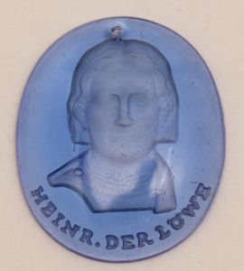 Militaria, Alemanha II Guerra. Proveniente de importante coleção adquirida na Bélgica - Feira de Militaria de Ciney. O partido nazista promoveu uma grande campanha de arrecadação de fundos antes e durante a guerra, com a venda de itens colecionáveis, pins, pendentes, tinnies, badges etc. Sempre colecionáveis voltada a novas compras. Oportunidade para colecionador avançado. **Item não promove ou glorifica violência ou intolerância racial. Está à venda apenas para fins de preservação da memória histórica. A Organização do leilão não faz apologia a quaisquer movimentos políticos ou ideológicos, e repudia qualquer ideologia de cunho racista.WHW - Campanha de Inverno em vidro. Personalidade. 30x35 mm. Heine Der Lowe. Alta cotação. Rei Henrique.