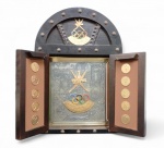 Quadro  em madeira escura entalhada em estilo rústico com 2 portas frontais com tachas e fechadura com  chapa de metal prateado esculpido no fundo em relevo , Brasão de Omã  e  anéis olímpicos   e nas laterais medalhas comemorativas da Olimpíadas , presenteado para atletas , autoridades  pelo  OMAN OLYMPIC COMMITTEE ,  medindo 5 x 44 x 31 cm Peça de colecionador