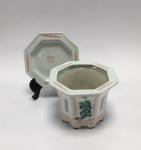 China / Jingdezhen. Porcelana de pasta dura.Cachepot com sousplat. Octogonal. Quatro painéis, decorados com flores de ameixas, orquídeas, bambu e crisântemos.  Simboliza a busca permanente de autoconsciência.   Valoriza atitude nobre, virtude, gentileza e independência.Outros quatro painéis com caracteres chineses.Sousplat com marca no centro. Excelente estado de conservaçãoAltura 11.5 x 15 cm.