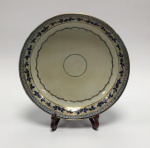 China / Cia. das Índias, Dinastia Qing, Período Jiaqing (1796 a 1820). Excelente porcelana Jingdezhen de pasta dura em cores azul, branco, ouro e verde. Prato de porcelana encomenda do Portugal. Clássica decoração de folhas de videira, cachos de uvas, perolados e ramos. Faixas e frisos com ornamentos na borda. Famille rose, pintura overglazed. No verso há marcas de pinos (suportes) de queima, garantia de uma queima perfeita. Vestígios de restauro. Restauro profissional, percebido com olhar próximo e atento.