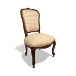 Cadeira de calçar botas de estilo francês Luís XV em madeira entalhada em florões, linhas curvas elegantes e estofado clássico em padrão floral miúdo. Peça de época com charme francês e presença decorativa. Mede 90 x 50 cm.