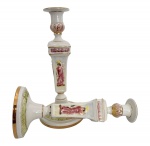ITALIA - Par de castiçais em porcelana italiana Capodimonte, ricamente decorados com cenas clássicas de figuras humanas em relevo policromado, detalhes em douração e base trabalhada. Peças elegantes, de fino acabamento, típicas da tradição italiana decorativa do século XX. contorno em vibrante ouro. Mede 32 cm altura.