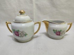 Jogo de açucareiro e cremeira em porcelana Rami floral com friso ouro. Medindo o açucareiro 8cm de altura.