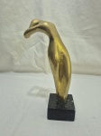 Escultura moderna abstrata em bronze maciço representando figura estilizada inclinada, assinada Daisy 24/90, com acabamento polido e marcas naturais do tempo, fixada sobre base cúbica em mármore escuro, peça de caráter artístico e decorativo. Medindo 22,5cm de altura.