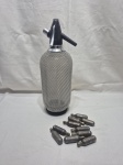 Antigo sifão de soda com malha em metal prateado e capsulas vazias de co2. Medindo 36cm de altura.