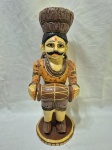 Escultura decorativa artesanal em madeira entalhada e policromada, representando figura masculina de músico Rajasthani em trajes tradicionais, com bigode característico, mãos em gesto de saudação/oferta, apoiada sobre base circular em madeira, apresentando pátina do tempo e desgastes naturais da policromia, peça de caráter étnico e decorativo. Medindo 33cm de altura. Com perda no esmalte.