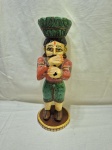 Escultura decorativa artesanal em madeira entalhada e policromada, representando figura masculina de músico Rajasthani em trajes tradicionais, com bigode característico, mãos em gesto de saudação/oferta, apoiada sobre base circular em madeira, apresentando pátina do tempo e desgastes naturais da policromia, peça de caráter étnico e decorativo, em bom estado estrutural. Medindo 33cm de altura. Com perda no esmalte. Faltando instrumento.