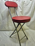 Linda banqueta com encosto em metal cinza, acolchoamento vermelho, peça dobrável. Medindo 30cm de diâmetro x 72cm de altura x 83cm de comprimento fechado.
