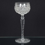 BACCARAT, uma (1) taça de pé alto para vinho, incolor e translúcida, bojo lapidado em palmas, sulcos e estrelas, fuste hexagonal no formato de balaustre com serrilhado, base em bolacha, fundo estrelado, meados do século XX, medindo 20 cm altura, sinais de uso, vide foto.