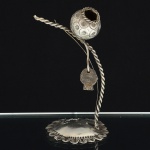 ESCULTURA, uma (1) representando berimbau, confeccionada em metal prateado, souvenir da Bahia, medindo 15cm altura, vide foto.