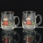 VIDRO, par (2) canecas, incolores e translúcidas, souvenires de Nazaré, Portugal, ornadas com barco, pescador emulher com trajes típicos, medindo 9 cm altura, vide foto.