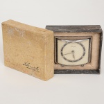 RELÓGIO, um (1) despertador de viagem, padrão Art Deco, gabinete em metal cromado, marca KIENZLE,acondicionado na caixa original (caixa no estado), funcionando e sem garantia, medindo 7 x 5,5 x 2,5 cm, vide foto.