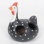 Peça utilitária confeccionada em cerâmica representando uma galinha, decorada com pintura artesanal em preto, com bolinhas brancas, e detalhes em vermelho e branco na cabeça. A estrutura possui duas aberturas laterais, indicadas para uso como porta-colheres ou porta-utensílios de cozinha. Apresenta desgaste no bico. Med.: Alt. 12,5 x Diam. 14 cm.