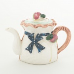 LOUÇA, um (1) pequeno bule com tampa, modelado na forma de saco com laçarote e frutas relevadas, pintado amão em policromia, sem marca de manufatura aparente, medindo 12 cm altura, falhas na esmaltação, sinais de uso, videfoto.