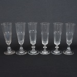 VIDRO, seis (6) flutes de pé alto, incolores e translúcidos, bojo obcônico com metade inferior lapidação dedão,fuste no formato de balaustre, base em bolacha, medindo 17,5 cm altura, sinais de uso, vide foto.