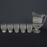 VIDRO, conjunto com seis (6) itens, incolores e translúcidos: 1 jarra refresqueira e 5 copos, bojo canelado navertical com faixa acetinada na horizontal, relevada em pássaros e parras na jarra e mulheres nuas e parras nos copos, medindo a maior peça 26 cm altura, todos os itens com sinais de uso, vide foto.