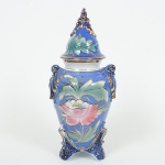 PORCELANA, um (1) vaso com tampa tipo balaustre, modelagem relevada em folhas, losangos e outroselementos vegetalistas, pintado a mão em policromia, arremates a ouro, sem marca de manufatura aparente, numerado40 em cavo na base, medindo 31 cm altura, sinais de uso, vide foto.