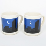 FAIANÇA INGLESA, par (2) canecas ornadas com silhueta de paisagem noturna metropolitana, tonalidades azul e preta sobre fundo branco, medindo 9,5 cm altura, vide foto.