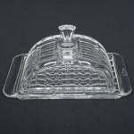 VIDRO, uma (1) manteigueira com tampa, incolor e translúcida, moldada em sulcos, medindo 20 x 12,5 x 10 cm, sinais de uso, vide foto.