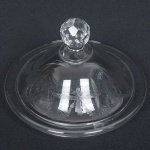 VIDRO, uma (1) tampa para compoteira, incolor e translúcida, ornada com barrado contínuo em guirlandas de flores, pega facetada, padrão Saint Louis, medindo 17 cm diâmetro, sinais de uso, vide foto.