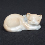 ESCULTURA, uma (1) representando gato dormindo, confeccionada em porcelana policromada em tons pasteis, sem marca de manufatura aparente, medindo 7 cm comprimento, ideal para coleção de bibelô, vide foto.