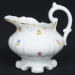 PORCELANA PORTUGUESA, uma (1) cremeira, ornamentação floral policromada, arremates a ouro, manufatura VISTA ALEGRE (fundada em 1824, pelo negociante, lavrador, industrial e político, José Ferreira Pinto Basto, através de alvará concedido por D. João VI, tendo seu fundador associado a fábrica os seus 15 filhos, ficando a sociedade denominada Ferreira Pinto & Filhos; cinco anos mais tarde recebe o título real pelo reconhecimento de sua arte e sucesso, ficando conhecida como Real Fábrica da Vista Alegre, começou no fabrico de vidros enquanto se empenhava em esforços para a produção de porcelana, os primeiros ensaios conseguidos foram imperfeitos denominado loiça de pó de pedra, através de boas relações com a fábrica francesa de Sevres conseguiu as receitas para o fabrico de porcelana, somente em 1832, por sorte, é encontrado um jazigo de caulim situado em Aveiro, próximo a Ílhavo, a partir desta data o fabrico de porcelana foi se aperfeiçoando em Portugal, 1851 expôs com sucesso no Palácio de Cristal em Londres; 1852 D. Fernando II visita a fábrica e encomenda uma baixela completa; 1867 recebeu sua primeira premiação na Exposição Universal de Paris; 1880 interrompe a produção de vidros para se dedicar exclusivamente a porcelana; 1964 inauguração do Museu Histórico da Vista Alegre; ainda em funcionamento), medindo 14 cm altura até a alça, ideal para coleção de cristaleira, vide foto.