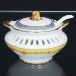 PORCELANA, uma (1) molheira com tampa e concha, vazada na metade superior, ornada com faixa na tonalidade azul, arremates a ouro, metade inferior com faixa amarela e flores em policromia, sem marca de manufatura aparente, medindo 8,5 cm diâmetro, ideal para coleção de cristaleira, vide foto.